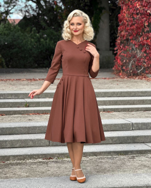 Sukienka z kopertowym dekoltem Vivian w cynamonowym brązie, z rozkloszowanym dołem i rękawami 3/4, prezentowana na modelce od przodu.